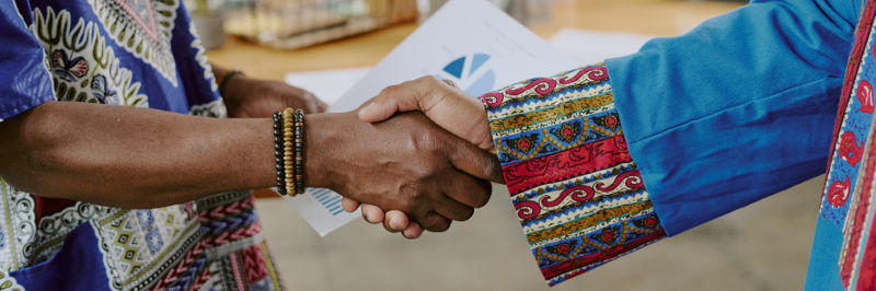 Two men in tribal garb shaking hands